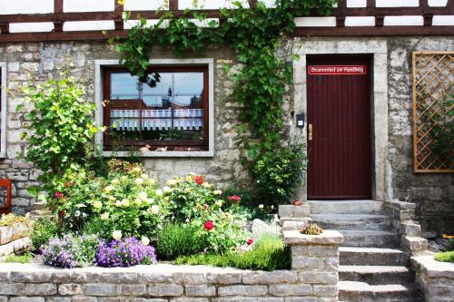 ein Haus mit einer roten Tür und ein paar Blumen in der Unterkunft Brunnenhof Randersacker - das kleine Hotel in Randersacker