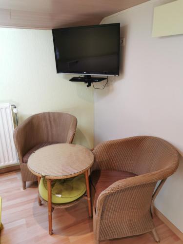 a room with two chairs and a table and a tv at Hôtel Belair "Ravel Etape" in Waimes