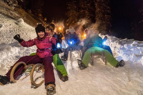 a group of people sitting in the snow at night at Basekamp Mountain Budget Hotel in Katschberghöhe