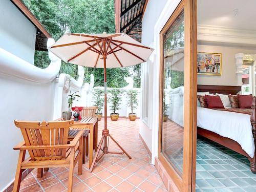a bedroom with a table and a large umbrella at MonPanaNont Wellness Resort & Spa in Mae Taeng