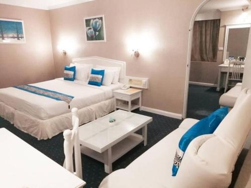 a hotel room with two beds and a couch at Bay Hotel Srinakarin in Bangna