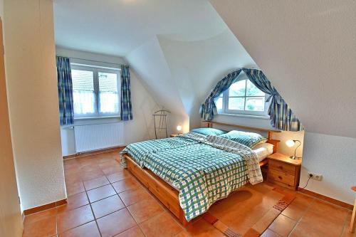 ein Schlafzimmer mit einem Bett und zwei Fenstern in der Unterkunft Ferienhaus An der alten Waldschänke WS-11a in Born