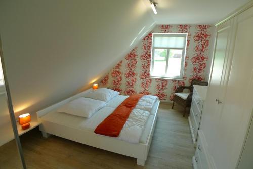 a bedroom with a white bed with a red wall at Haus STRANDHAFER WF-06 (links) in Wustrow