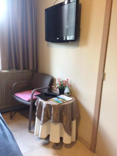 a room with a table and a tv on a wall at B&B Don Genaro in Dilsen-Stokkem