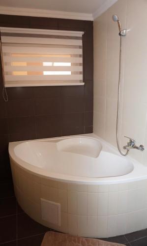 a bath tub in a bathroom with a window and a sink at Toscana 2 Debrecen in Debrecen