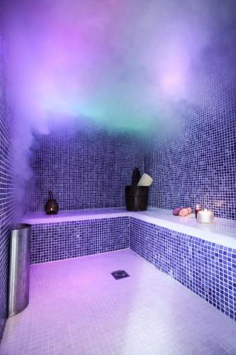 La salle de bains est pourvue de murs carrelés bleus et d'un sol blanc. dans l'établissement Sources en Périgord, à Issigeac