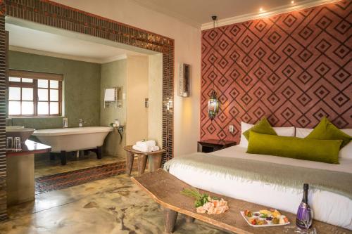 a room with a bed, a tub, and a painting on the wall at Singa Lodge - Lion Roars Hotels & Lodges in Port Elizabeth