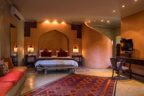 a bedroom with a bed and a couch in a room at Singa Lodge - Lion Roars Hotels & Lodges in Port Elizabeth