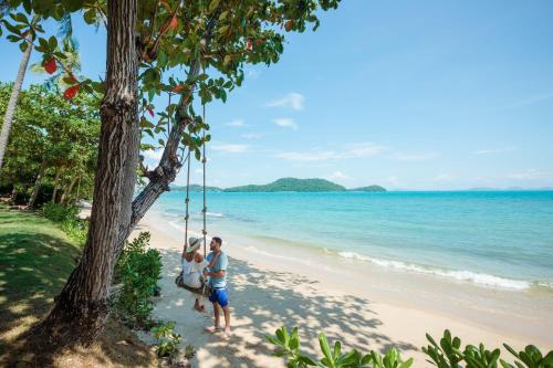 two people on a swing on the beach at Amatara Welleisure Resort in Panwa Beach