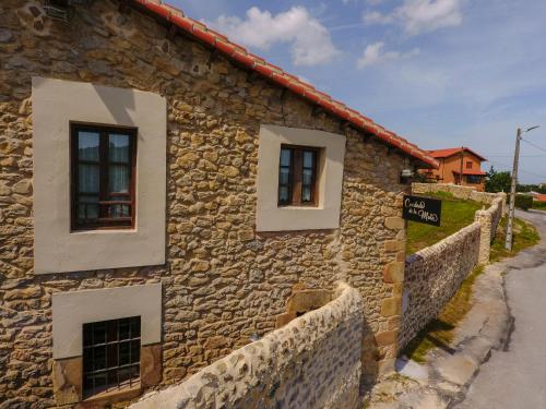 a stone building with two windows on a street at Posada Condado de la Mota in Mogro