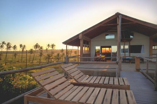 a house with a deck with a table and benches at Musica do Mar Beach Front Apartments, Ocean View in Praia do Tofo