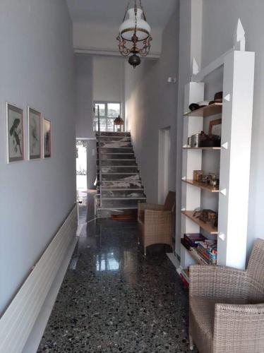 a hallway with a staircase with chairs and a chandelier at New Garden's House (120m2) in Leonidion