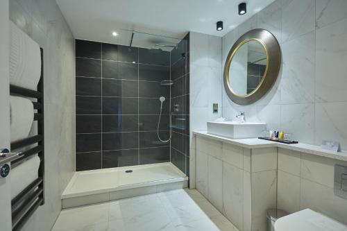 a bathroom with a shower and a sink and a mirror at Wychwood Park Hotel and Golf Club in Crewe