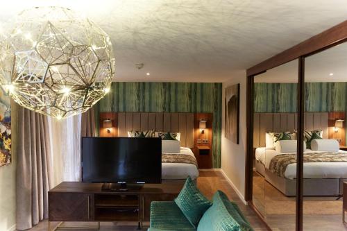 1 dormitorio con 2 camas, TV y lámpara de araña en Wychwood Park Hotel and Golf Club, en Crewe