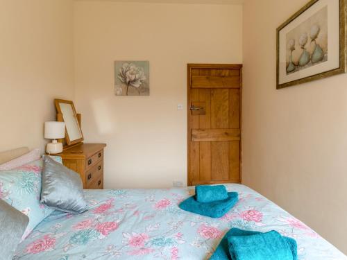 a bedroom with a bed with blue sheets and a wooden door at Old Town Cottage in Ludlow