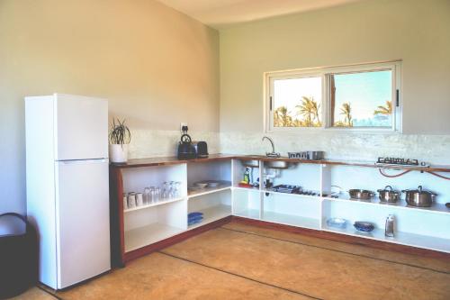 a kitchen with a white refrigerator and shelves at Musica do Mar Beach Front Apartments, Garden View in Praia do Tofo