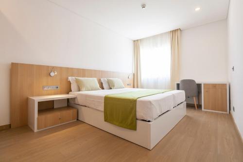 a bedroom with a large bed and a desk at Hotel Da Luz in Santa Maria