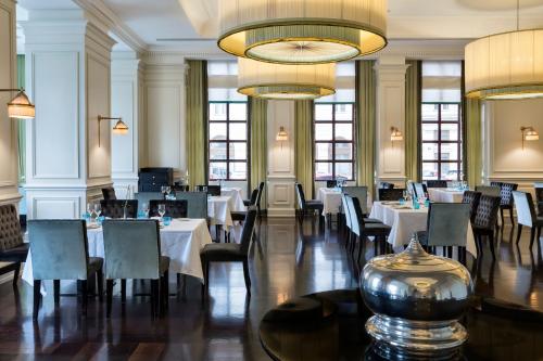 a restaurant with tables and chairs and a large chandelier at Savoia Excelsior Palace Trieste - Starhotels Collezione in Trieste