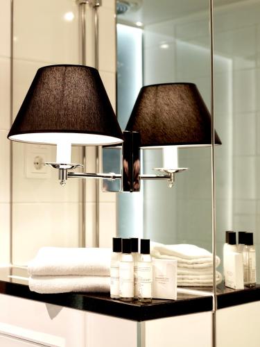 a bathroom with a mirror and a lamp and towels at Arctic Light Hotel in Rovaniemi
