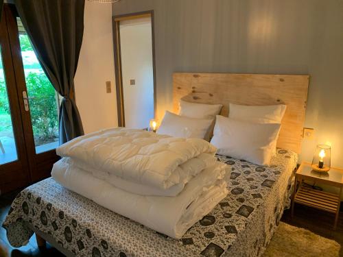 een slaapkamer met een groot bed met witte lakens en kussens bij Le Chant des Pierres - Entre Terre et Mer in Pornic