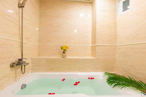 a bath tub with a vase of flowers in a bathroom at Galaxy Hotel Phu Quoc in Phu Quoc