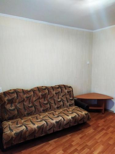 ein braunes Sofa in einem Zimmer mit einem Tisch in der Unterkunft Прокофьева 24б Уютная посуточная квартира in Sumy