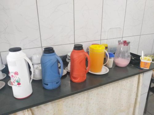 un grupo de botellas de diferentes colores sentadas en un mostrador en Hotel Casa Grande Max, en Marília