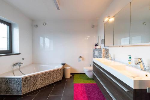 a bathroom with a tub and a sink and a toilet at La Maison de Marie in Borgloon