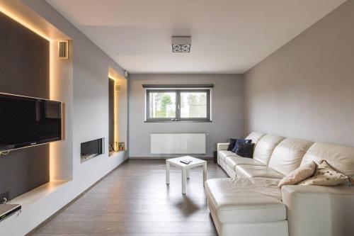 a living room with a white couch and a tv at La Maison de Marie in Borgloon
