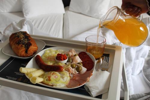 a tray of breakfast food on a bed with a drink at Garni Hotel 11tica DM in Novi Sad
