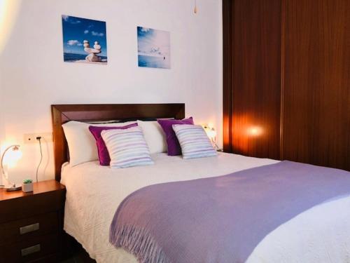 a bedroom with a bed with purple and white pillows at Jimena in Fuengirola