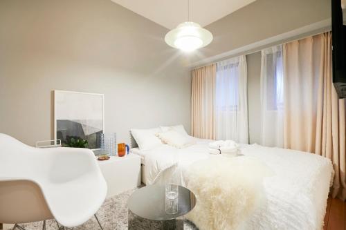 um quarto branco com 2 camas e uma cadeira em P OIN T - Shinjuku Kabukicho Designer's Apartment I em Tóquio