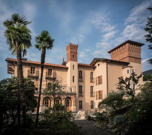 a large building with a palm tree in front of it at Castellino Bella Vista in Ponte Tresa