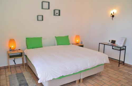 a bedroom with a large white bed with green pillows at B&B Quinta O Ninho in Monchique