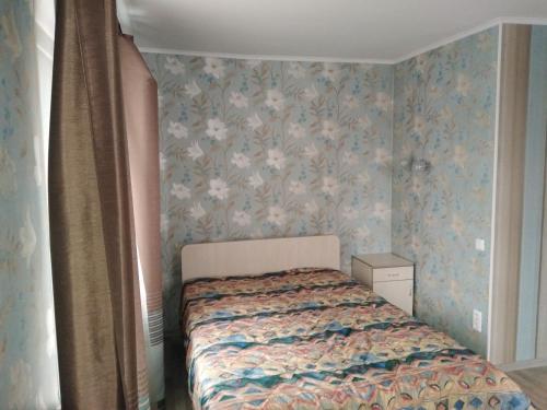 um pequeno quarto com uma cama com papel de parede floral em Sparta Apartments Kosmonaudi em Narva