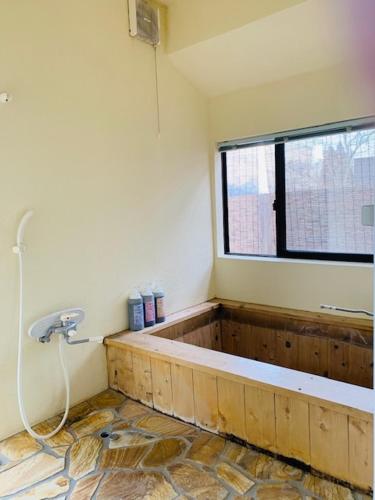 a bathroom with a bath tub with a window at Yufuin-Sanso Waremokou in Yufuin