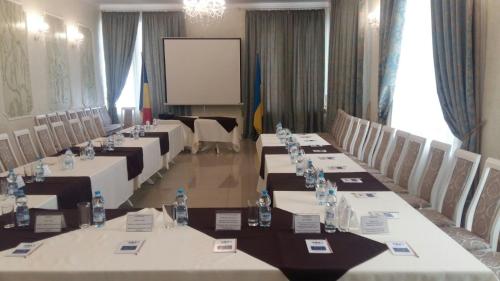 a conference room with long tables and chairs and a screen at Отель БЕССАРАБИЯ in Izmail