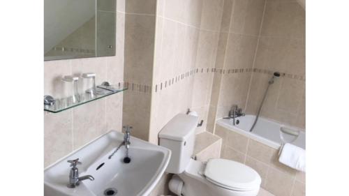 a bathroom with a toilet and a tub and a sink at Runnymede Court Hotel in Saint Helier Jersey