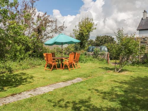a table and chairs with an umbrella in the grass at Minffordd in Newborough