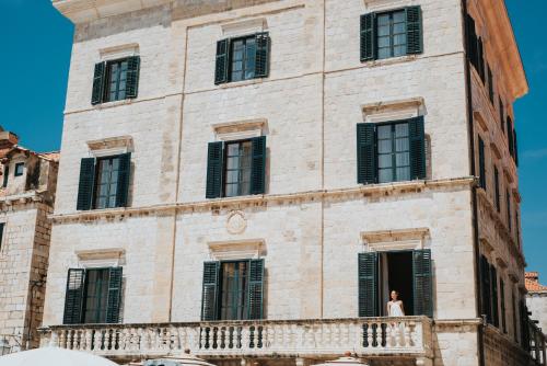 a woman standing on a balcony of a building at The Pucic Palace in Dubrovnik