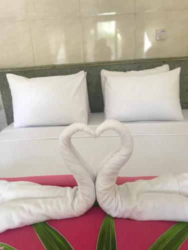 a bed with two towels in the shape of a heart at Tasik Dumun Homestay and Waroeng in Amed