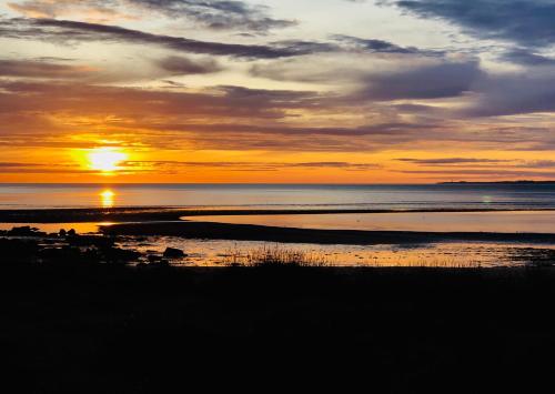 a sunset over the ocean with the sun setting at Albatross B&B Dornoch in Dornoch