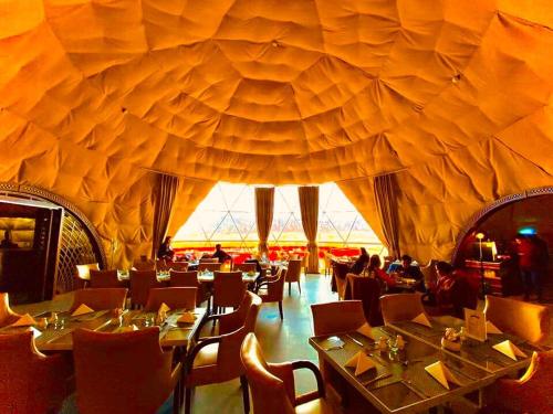 瓦迪拉姆的住宿－Wadi Rum UFO Luxotel，餐厅拥有带桌椅的大型天花板。