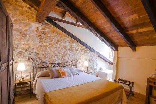 a bedroom with a bed in a stone wall at Posada Condado de la Mota in Mogro