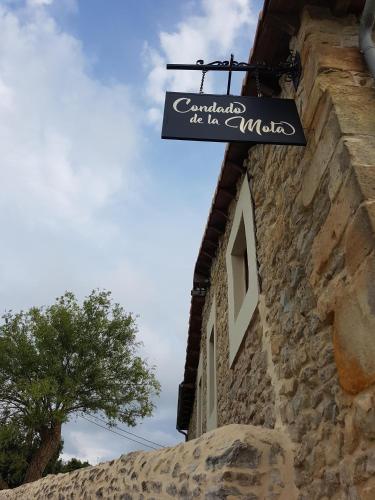 a sign hanging on the side of a stone building at Posada Condado de la Mota in Mogro