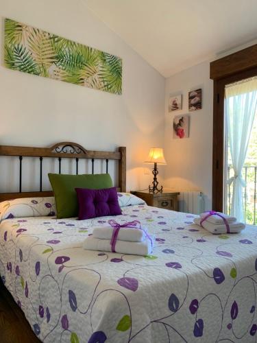 1 dormitorio con 1 cama grande con almohadas moradas en La Casa De La Abuela, en Ortigosa del Monte