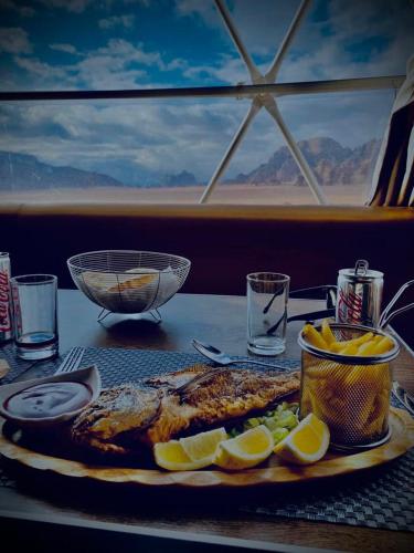 a plate of fish with lemon slices on a table at Wadi Rum UFO Luxotel in Wadi Rum