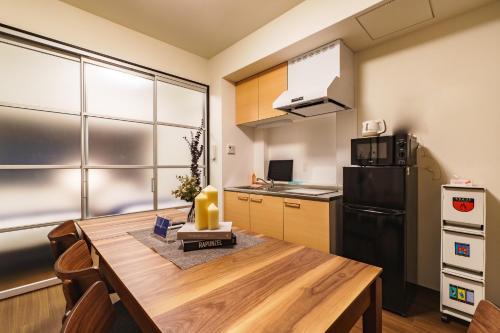 a kitchen with a wooden table and a black refrigerator at IKIDANE Residential Hotel SHIMANOUCHI in Osaka