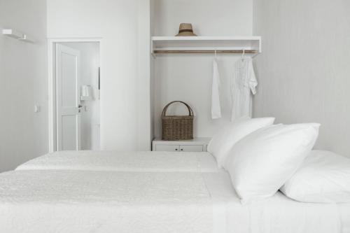 a white bedroom with a bed with white pillows at Terra Maria Hotel in Mýkonos City