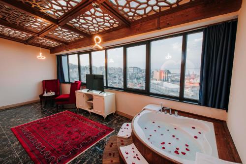 Habitación con bañera, TV y ventanas. en TS Gold Otel, en Trabzon